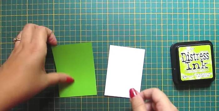 Prepare the tag base: Cut and shape white and green cardstock, using corner punch and stencils with ink/watercolors.