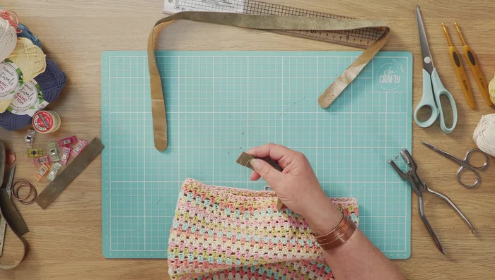 Sew the straps onto the bag. Start sewing into your inner strap a couple of times to secure the thread. Place the strap inside the bag, and sew through a stitch, avoiding sewing through a hole. Use a cross pattern (diagonal on the outside, side to side on the inside). Secure each strap by stitching through it at least three times.