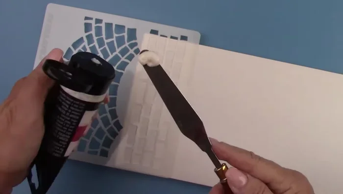 Spread texture paste over the stencil to create bricks and rocks.