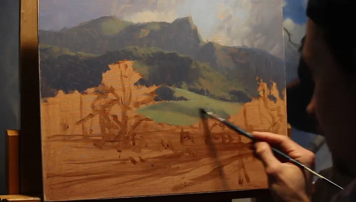 Establish the mid-ground with a #4 filbert brush, focusing on grassy slopes and a paddock meeting the forest. Ensure the greens are not overly saturated to keep them in the mid-ground.