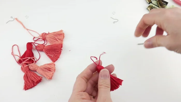 Assemble the earrings: Using a tapestry needle, thread the bottom tassels together, then add the middle tassels, and finally the top tassels, securing each layer with a knot.