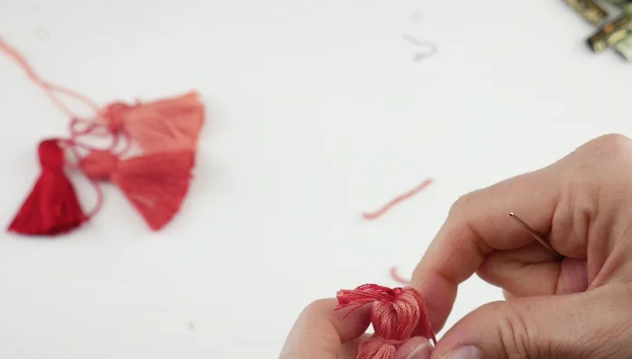 Weave in loose ends: Use a tapestry needle to tuck in all the remaining loose ends of the embroidery floss at each tier of the tassel.