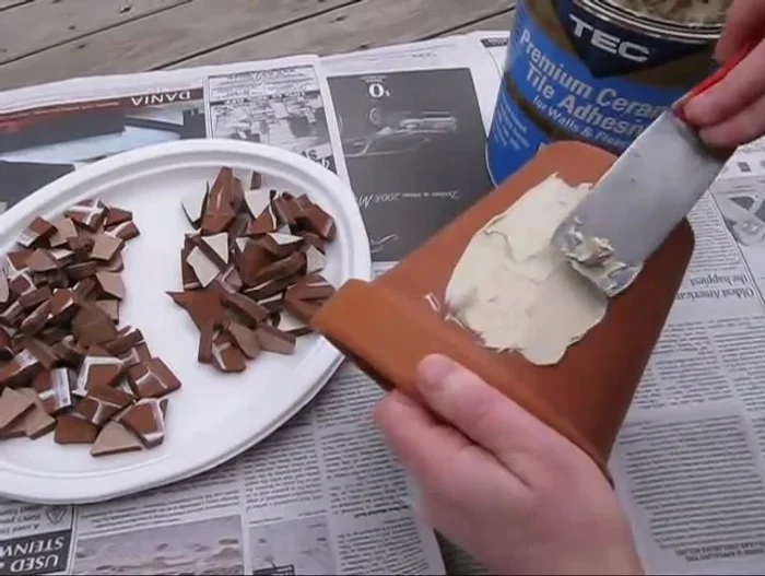 Spread tile adhesive evenly onto the pot, ensuring it doesn't go more than halfway up the tile's edge.