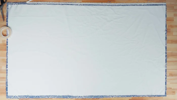 Use basting tape to fold and secure 1-inch seams along both side edges. Fold again, for another 1-inch seam; clip in place.