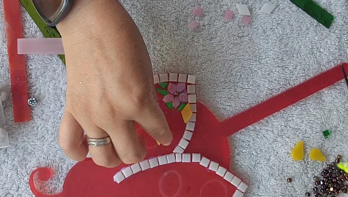 Cut and shape larger stained glass tiles into daisy shapes for the ladybug's body.