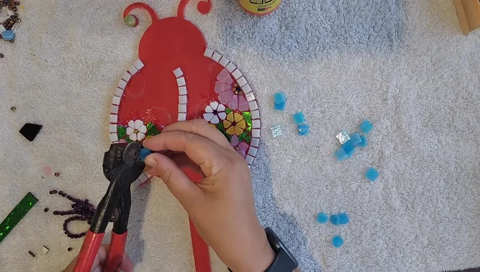 Cut and shape larger stained glass tiles into daisy shapes for the ladybug's body.