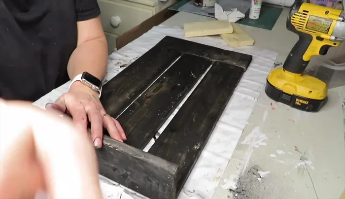 Assemble the mailbox frame by spacing the stained wood pieces evenly and attaching them with screws.