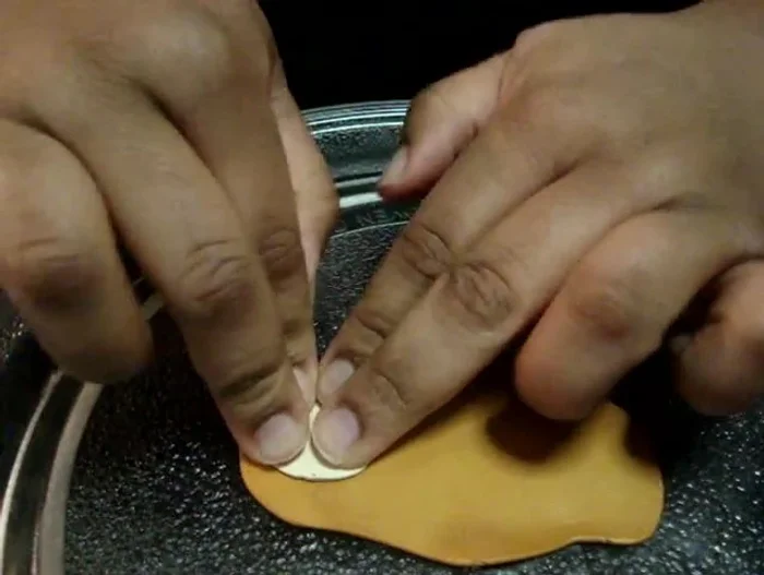 Use the baked clay grid as a stamp, pressing it gently into the colored clay to create the ice cream cone pattern. Use a small amount of oil to prevent sticking if needed.