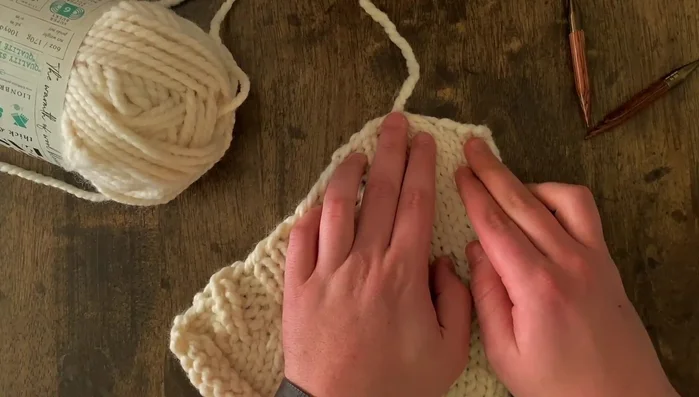 Sew the pocket onto the garment, ensuring the cast-on edge and bottom edge are horizontal.