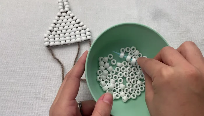 Bring the beads to your work, skip the last bead, and weave the needle through all the beads. Then, go back up and through the foundation beads.