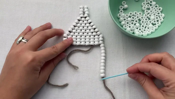 Bring the beads to your work, skip the last bead, and weave the needle through all the beads. Then, go back up and through the foundation beads.