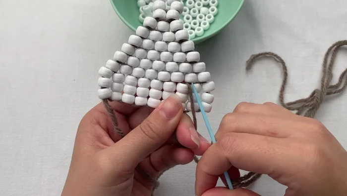 Tie a double knot to secure the loop. Grab the loop, thread your needle through once, wrap around, and pull tight.