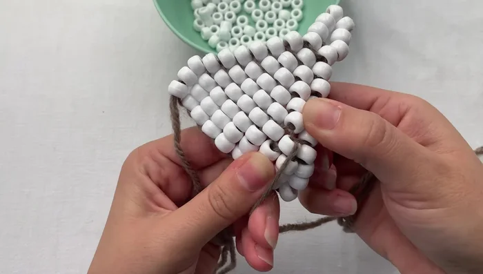 Tie a double knot to secure the loop. Grab the loop, thread your needle through once, wrap around, and pull tight.