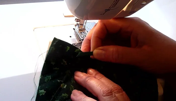 Insert ribbon: Insert the ribbon into the opening at the top of the tree, ensuring it's secure. Stitch around the top to secure the ribbon.