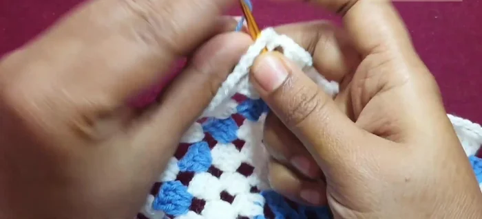 Adding blue yarn: Join blue yarn, repeat corner pattern, and then work one double crochet into each chain two space, separated by a chain one. Repeat around.