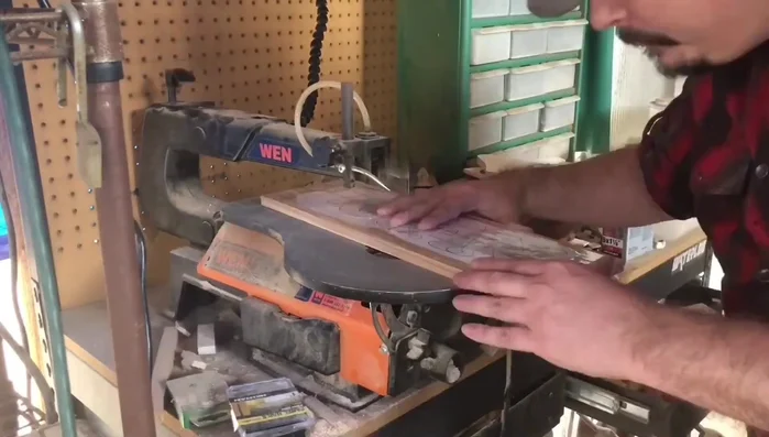 Cut out the nameplate design using a scroll saw. Don't worry about perfectly following the lines; it's okay to stray slightly. Smooth cuts are more important than precise accuracy.