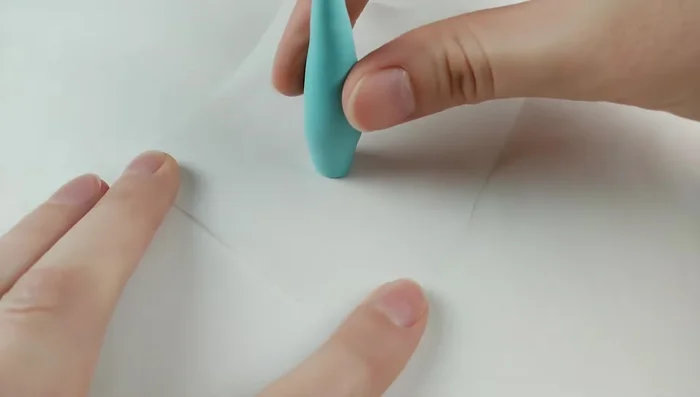 Roll out thicker blue clay, shape the body, bending neck and tail. Make a round head with indents for eyes and nostrils, and a smile.