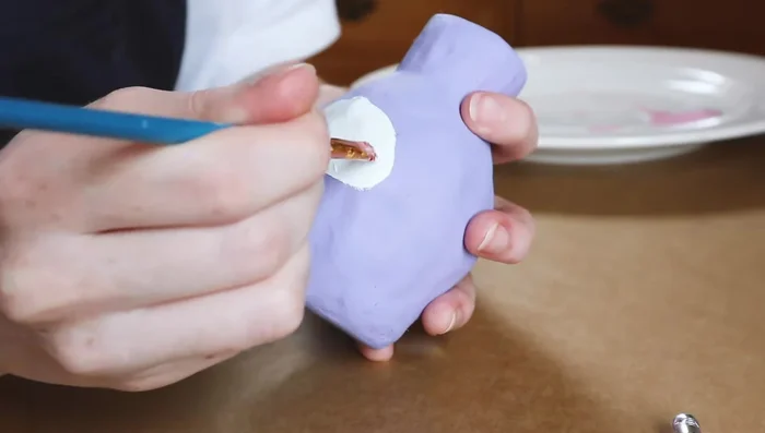 Paint faces on the vase using acrylic paint and add details with Posca pens.