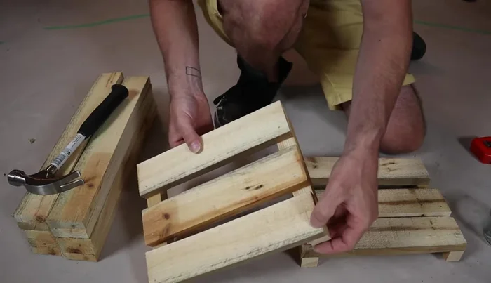 Flip the crate and attach the side slats, three per side. Again, start with one nail per piece to allow for adjustment and squaring.