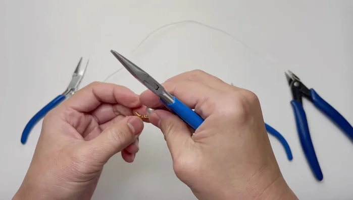 After trimming, adjust the wire wraps to ensure no sharp edges and a neat curve around the finger. Push down excess wire on either side to create a smooth, curved shape.
