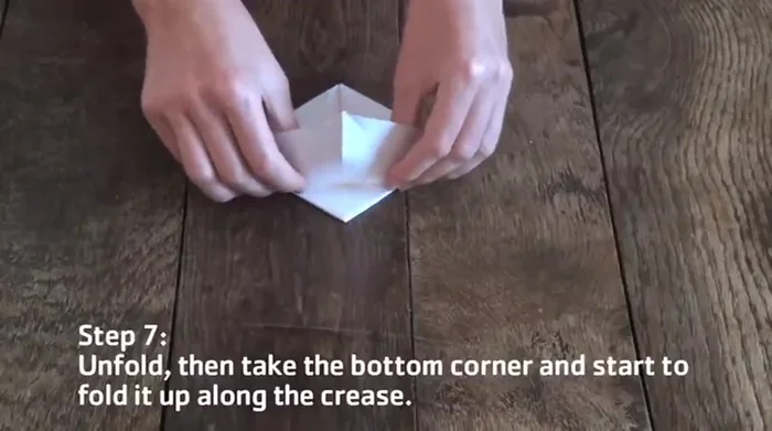 Take the bottom corner and fold it up along the horizontal crease. Reverse the two diagonal creases on the upper flap by folding them in the opposite direction. Bring the outer edges to the middle to form a diamond shape.