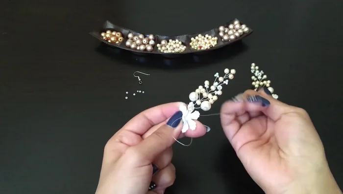 Add a small bead and secure the flower bead in the center using two additional pearls.