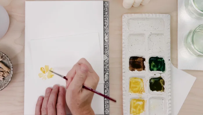 Paint yellow flower petals one at a time, using a few brushstrokes and leaving the paint alone to dry.