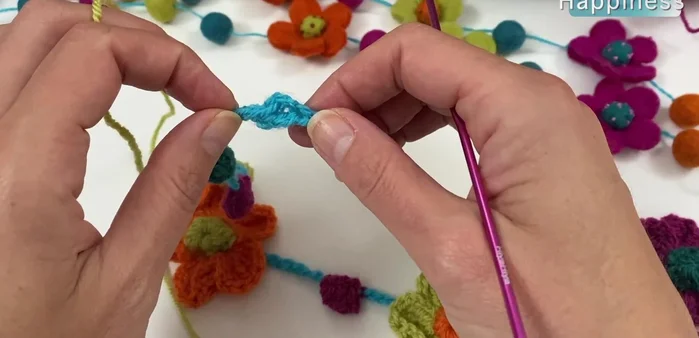 Construct the flowers: Using a 3 mm hook and the desired color (pistachio and pumpkin are shown), work 8 half double crochets into the prepared circle on the necklace. In the 8th stitch, work a half double crochet through the chain to join. Repeat on the other side of the circle.