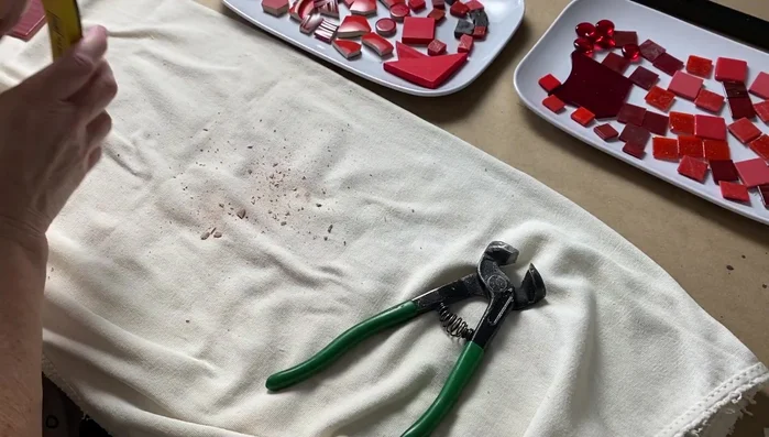 Tile the mosaic: Arrange the tesserae creatively, avoiding placing identical pieces next to each other. Work in sections if needed and wipe off excess adhesive.