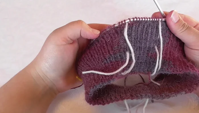 Slip one stitch, move yarn to the back, slip stitch back onto the left needle, turn. Purl back across sleeve and back stitches. Then, purl the last two stitches and continue to the next section.