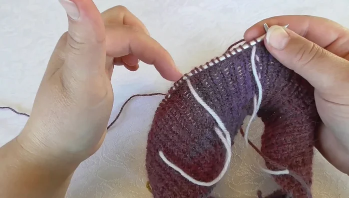 Slip one stitch, move yarn to the back, slip stitch back onto the left needle, turn. Purl back across sleeve and back stitches. Then, purl the last two stitches and continue to the next section.
