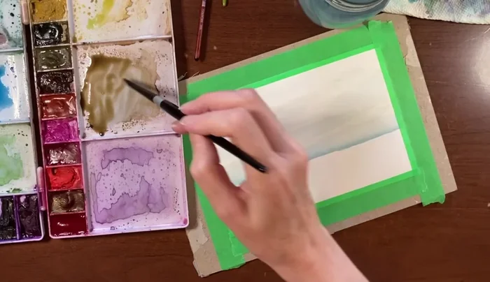 Apply a diluted sepia wash over the wet sand area, allowing the colors to blend naturally. The wash should be light and even.