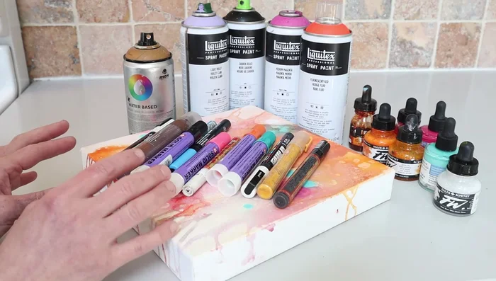 Continue layering with transparent acrylic inks, markers, and spray paints, focusing on mark-making and building transparent layers.