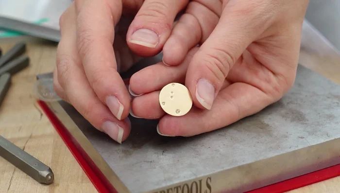 Flatten the stamped disc using a mallet.