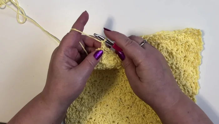 Change to contrasting color yarn. In each corner, single crochet, chain 1, single crochet. 