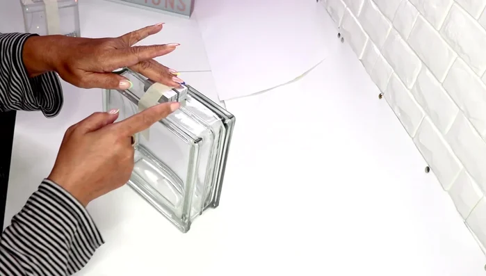 Glue four strips of mirror tile around the sides of the base, leaving the top plastic on for easier cutting.