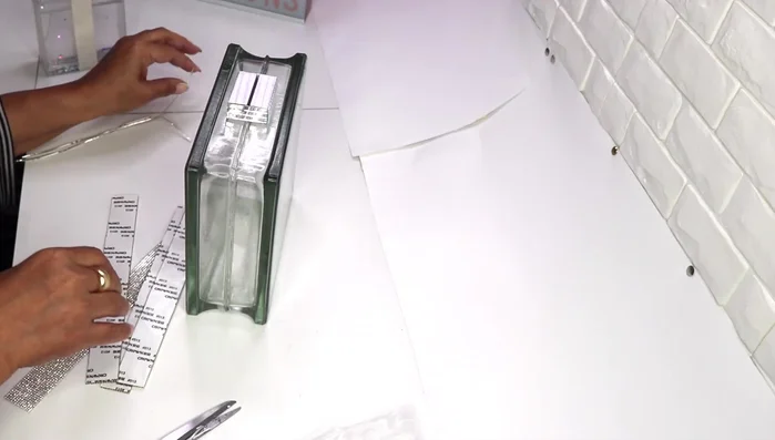 Glue four strips of mirror tile around the sides of the base, leaving the top plastic on for easier cutting.