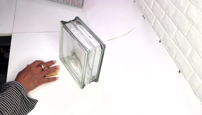 Glue two glitter photo frames from Dollar Tree together, ensuring the stoppers are at the bottom. Secure with masking tape.