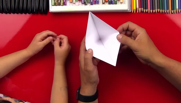Open the top layer to create a pocket shape. Fold the flaps down to create a diamond shape.