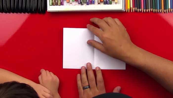 Open the paper to reveal a creased rectangle. Fold the bottom edges to the center crease.