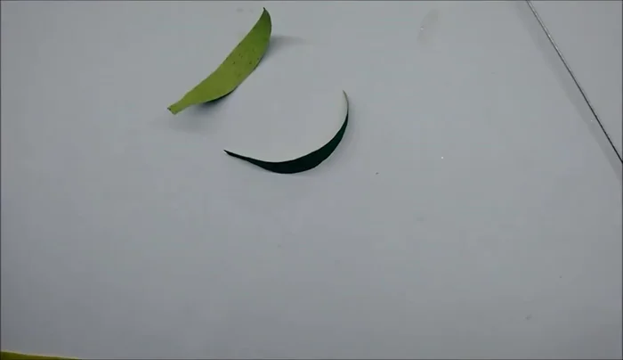 Curl the leaves slightly using scissors, wind green tape around the base of the flower, and attach the leaves to the tape.