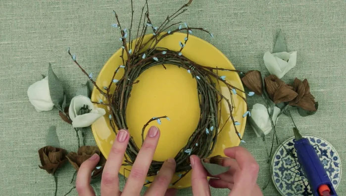 Once dry, add the flowers to the wreath base, attaching them with hot glue or by twisting the wire stems around the wreath.