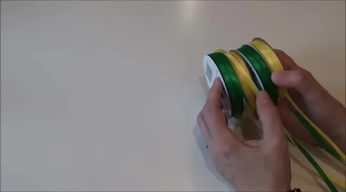 Create initial knots and loops: Tie a knot in one ribbon of each pair (your inside color), and create a loop in the other (your outside color). Leave a few inches of tail on each.