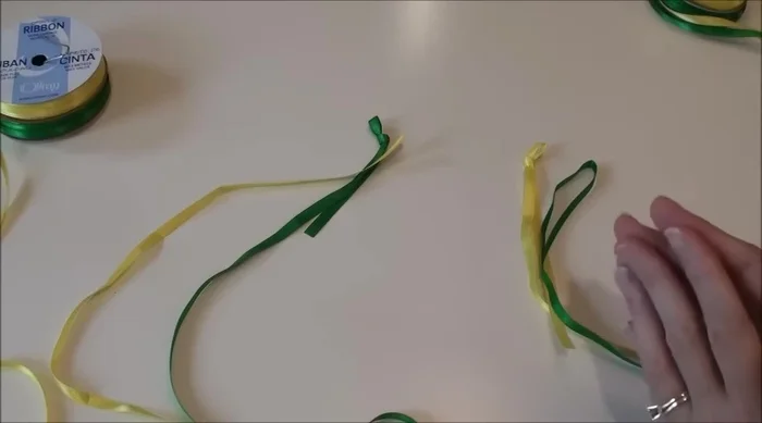 Create initial knots and loops: Tie a knot in one ribbon of each pair (your inside color), and create a loop in the other (your outside color). Leave a few inches of tail on each.