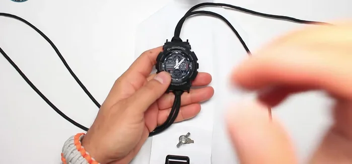 Place the paracord jig in the middle of the watch and insert one end of the black paracord into each side.