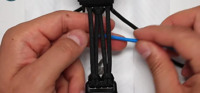 Weave the sky blue paracord around the black paracord, creating a secure attachment. Repeat this on both sides.