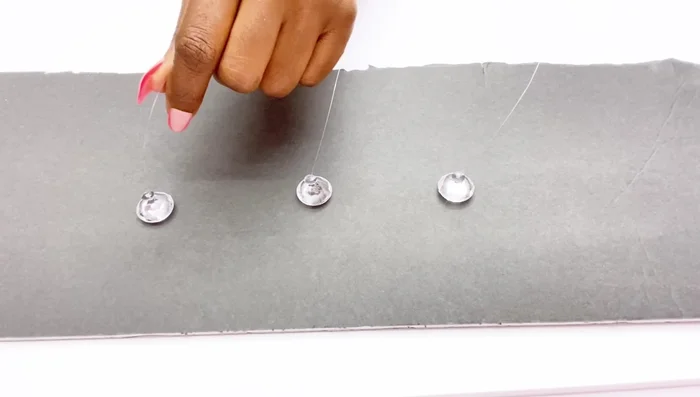 Attach the fishing lines with gems to the pens using a hot glue gun, ensuring the gems are upright.