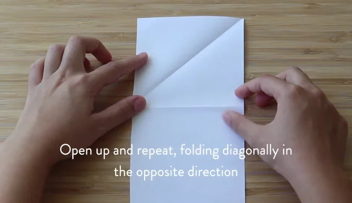 Fold the paper in half horizontally, then open it to reveal a horizontal line through the X.