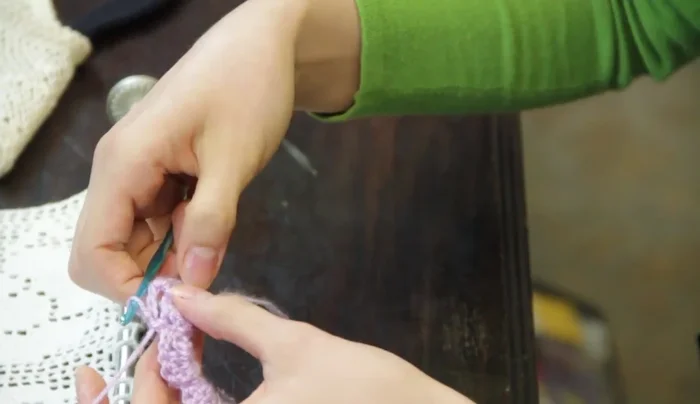 At the end of the row, chain three and attach it with a single crochet to the last double crochet in the shell from the previous row.