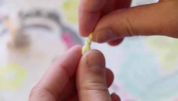 Make the horn: Twist two pieces of yellow Fimo gemstone clay together, cut off excess, and attach to the head.